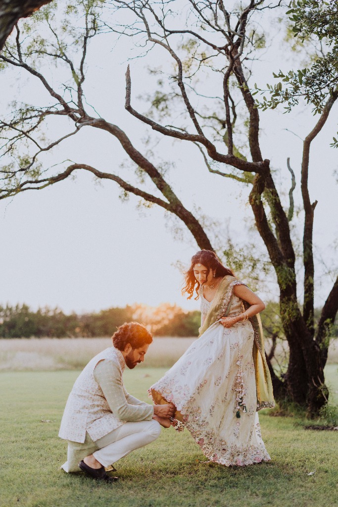 Nikhil fixing Sharvari's shoe in the grass